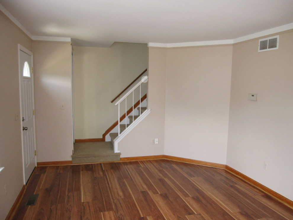 Ejemplo de salón cerrado actual grande con paredes beige, suelo laminado y suelo marrón