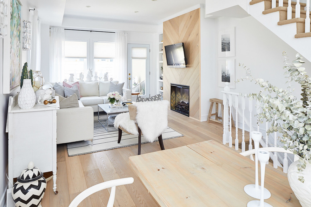 Aménagement d'un petit salon scandinave ouvert avec un mur blanc, parquet clair, une cheminée standard, un manteau de cheminée en bois et aucun téléviseur.