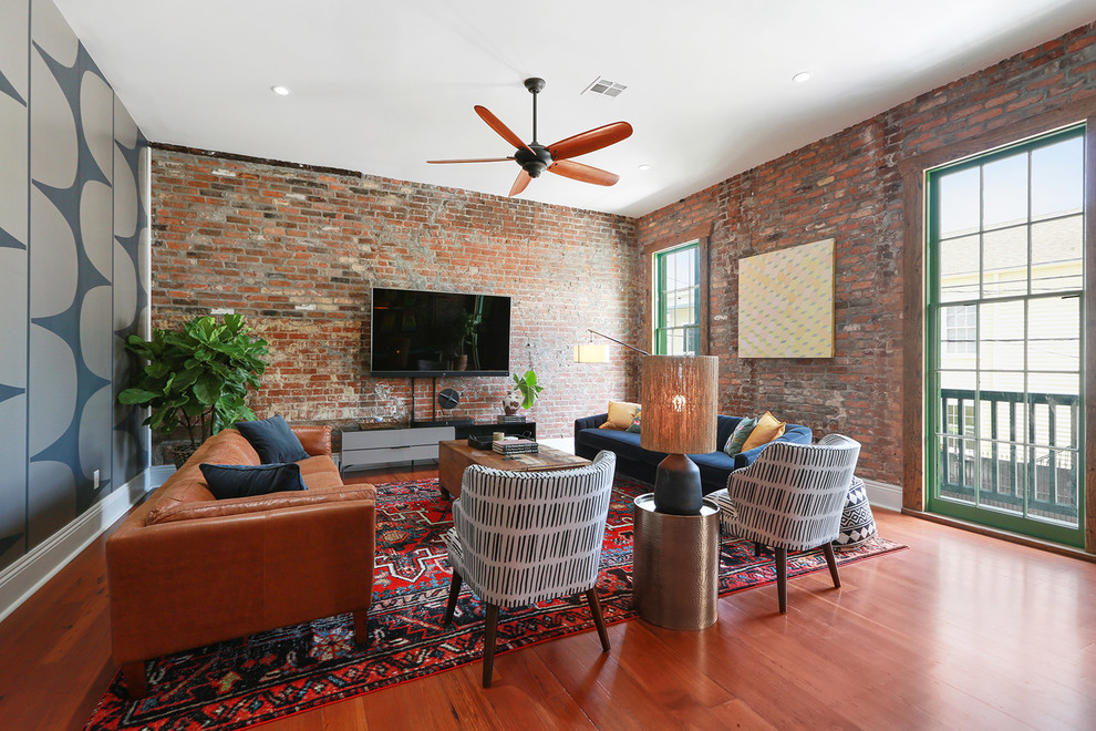 Inspiration for an industrial medium tone wood floor and brown floor living room remodel in New Orleans with blue walls and a wall-mounted tv