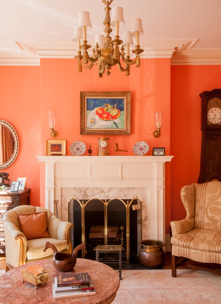Inspiration pour un salon traditionnel avec une salle de réception, un mur orange, un sol en bois brun, une cheminée standard et un manteau de cheminée en pierre.