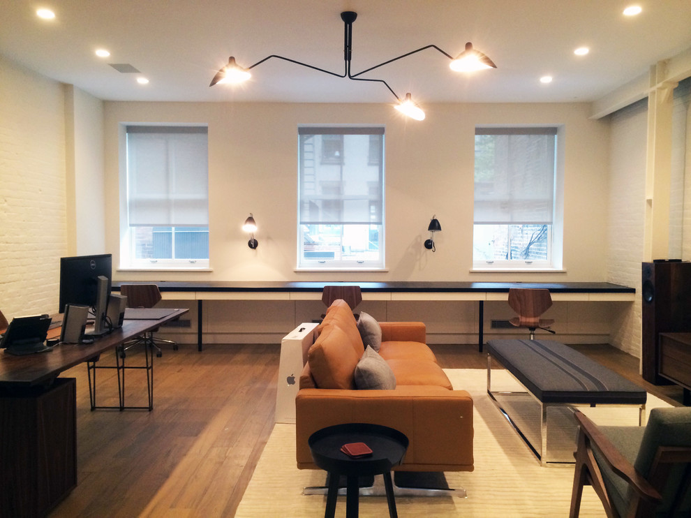 Medium sized modern open plan living room in New York with beige walls, medium hardwood flooring, no fireplace, a freestanding tv and brown floors.