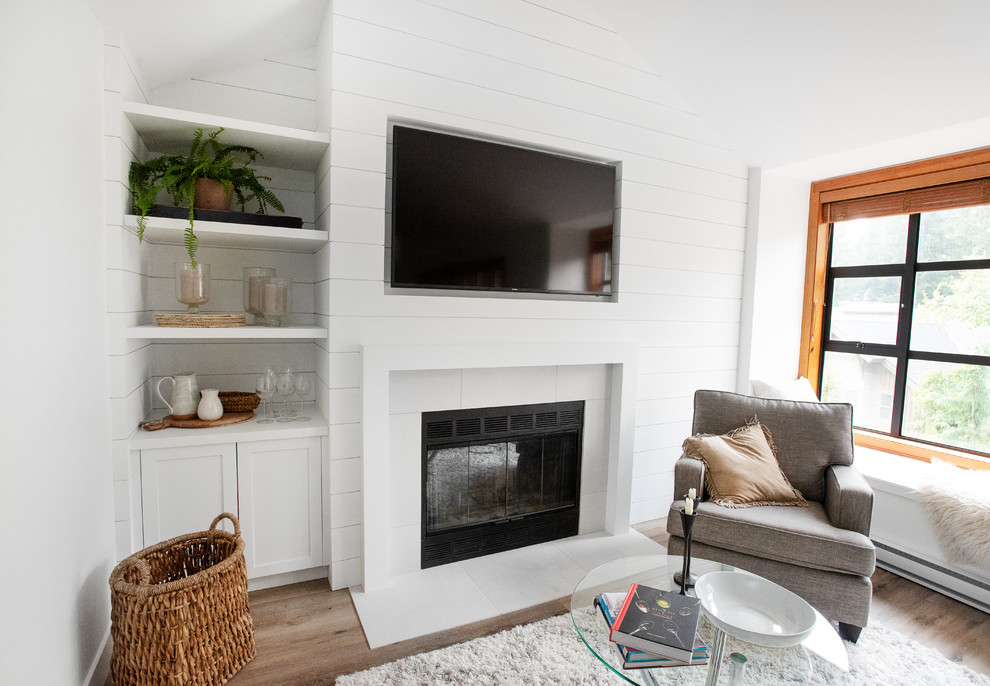 Idee per un piccolo soggiorno tradizionale aperto con pareti bianche, camino classico, cornice del camino piastrellata, TV a parete e pavimento marrone