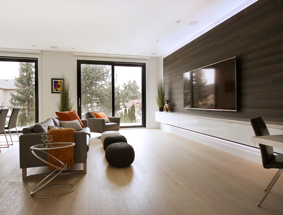 На фото: большая открытая гостиная комната в современном стиле с серыми стенами, светлым паркетным полом и телевизором на стене с