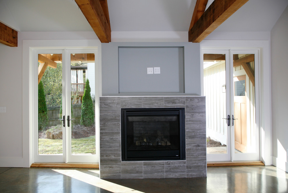 Foto på ett mellanstort amerikanskt allrum med öppen planlösning, med ett finrum, vita väggar, betonggolv, en standard öppen spis, en spiselkrans i trä och en väggmonterad TV