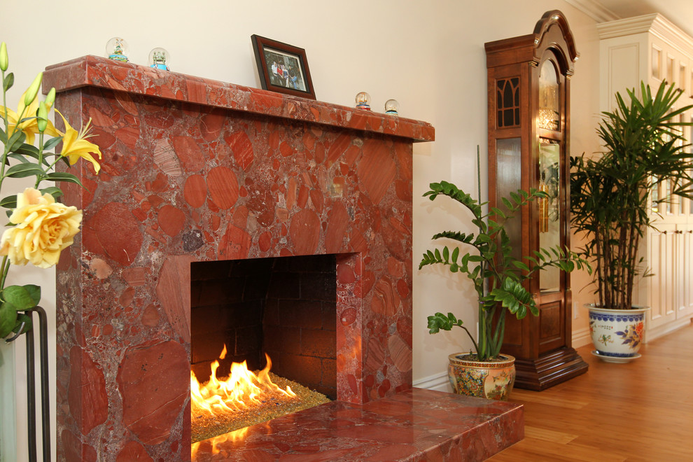 ロサンゼルスにあるお手頃価格の中くらいなトラディショナルスタイルのおしゃれなリビング (ベージュの壁、竹フローリング、標準型暖炉、石材の暖炉まわり、テレビなし、ベージュの床) の写真