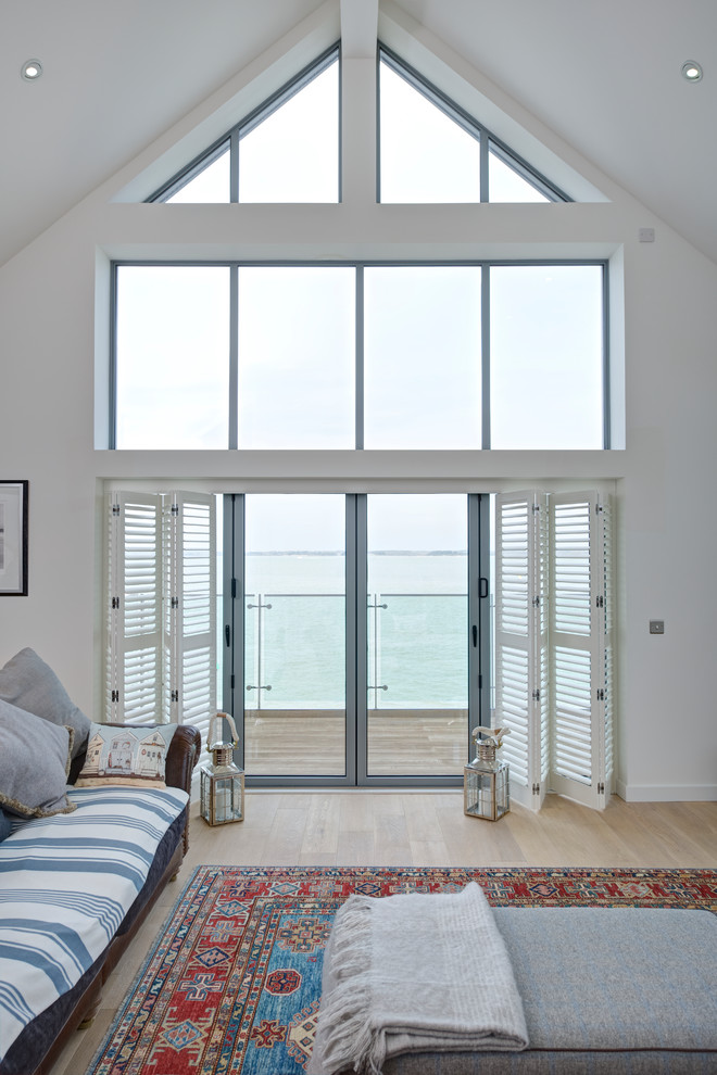 Immagine di un grande soggiorno costiero aperto con sala formale, pareti bianche, parquet chiaro, TV autoportante e pavimento beige