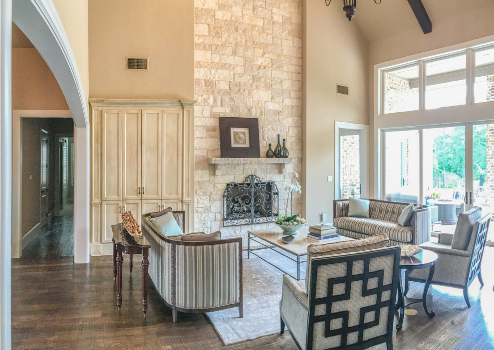 Mittelgroßes, Fernseherloses, Offenes Klassisches Wohnzimmer mit beiger Wandfarbe, braunem Holzboden, Kaminumrandung aus Stein und Kamin in Dallas
