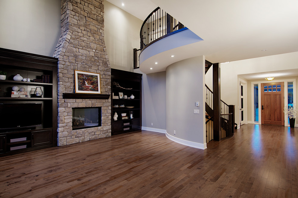 Стильный дизайн: гостиная комната в классическом стиле с серыми стенами, отдельно стоящим телевизором, паркетным полом среднего тона и фасадом камина из камня - последний тренд
