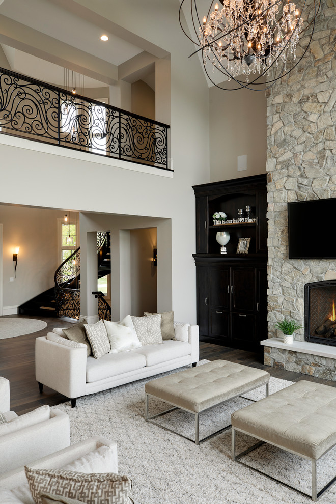 Inspiration pour un très grand salon traditionnel ouvert avec un mur beige, un sol en bois brun, une cheminée standard et un manteau de cheminée en pierre.