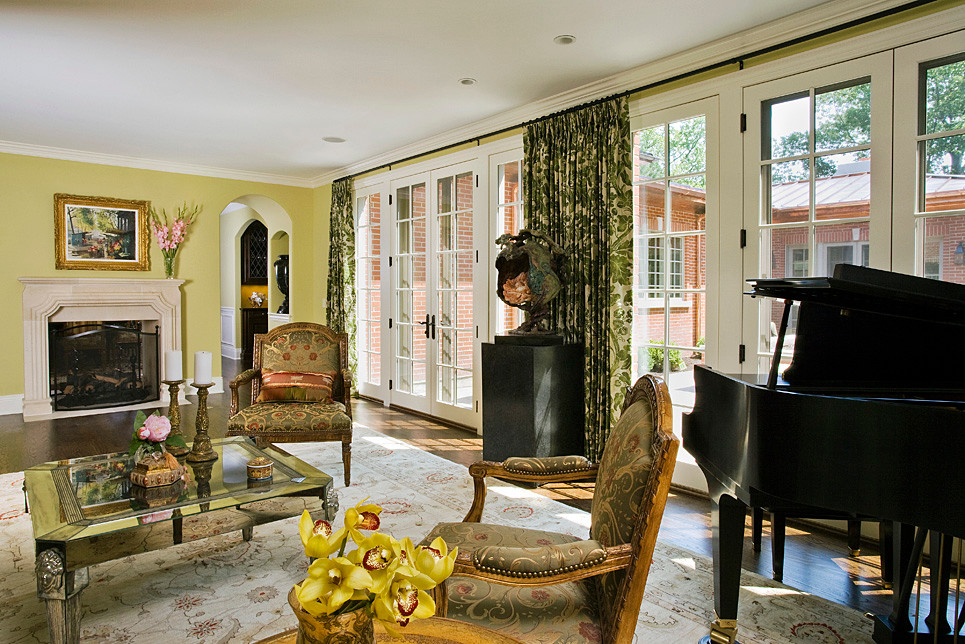 Пример оригинального дизайна: огромная изолированная гостиная комната в классическом стиле с желтыми стенами, темным паркетным полом, фасадом камина из камня и двусторонним камином