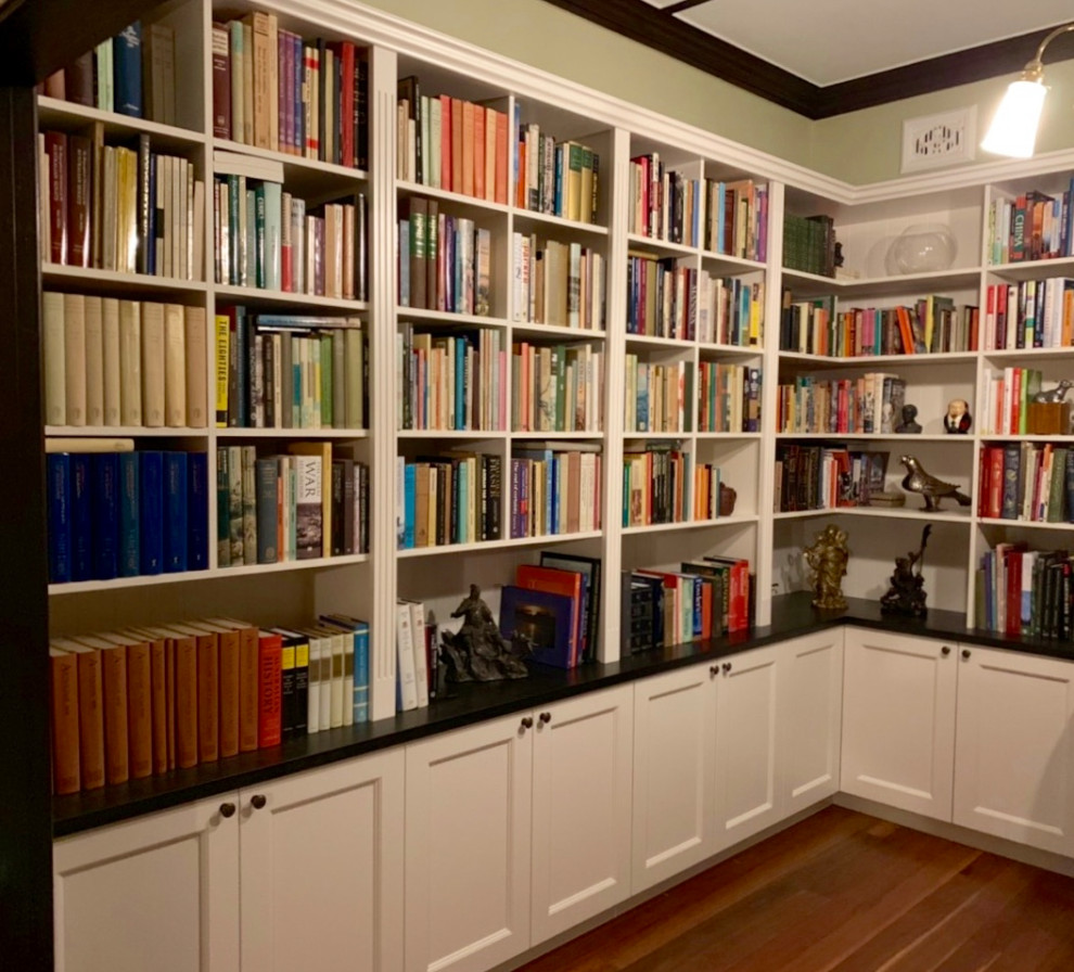 Ejemplo de biblioteca en casa clásica de tamaño medio con paredes verdes, suelo de madera oscura y suelo marrón