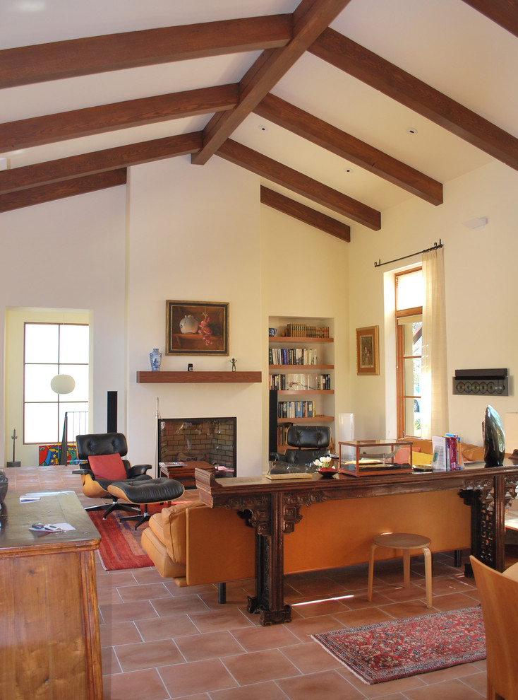 Ejemplo de biblioteca en casa abierta clásica con suelo de baldosas de terracota, paredes blancas y alfombra