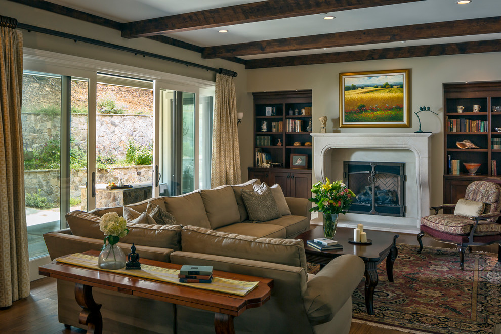 Exemple d'un grand salon chic ouvert avec une salle de réception, un mur beige, un sol en bois brun, un manteau de cheminée en pierre, une cheminée standard et aucun téléviseur.