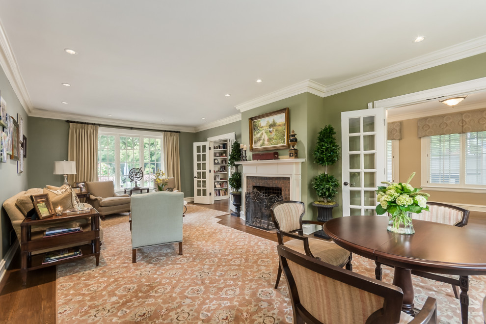 Стильный дизайн: большая открытая гостиная комната в классическом стиле с зелеными стенами, паркетным полом среднего тона, стандартным камином, фасадом камина из кирпича и разноцветным полом - последний тренд