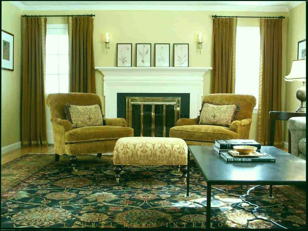 На фото: гостиная комната в классическом стиле с желтыми стенами, стандартным камином и красивыми шторами с