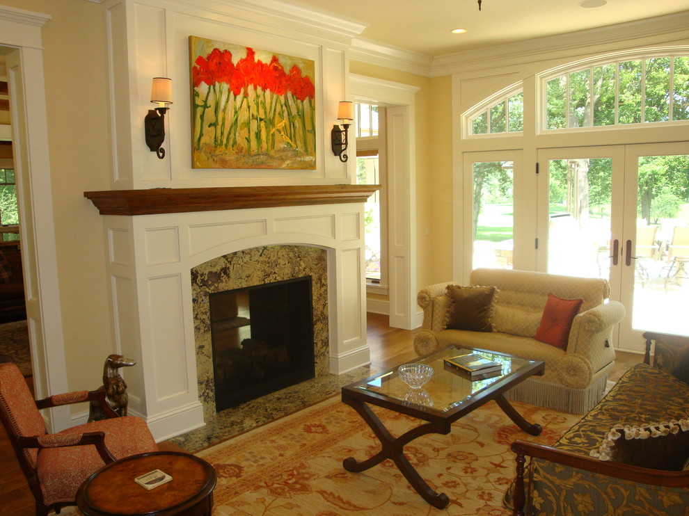 Inredning av ett klassiskt mellanstort vardagsrum, med ett finrum, gula väggar, heltäckningsmatta, en dubbelsidig öppen spis, en spiselkrans i sten och flerfärgat golv