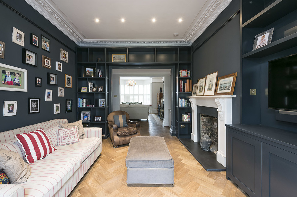 Inredning av ett klassiskt separat vardagsrum, med svarta väggar, ljust trägolv, en standard öppen spis och en väggmonterad TV
