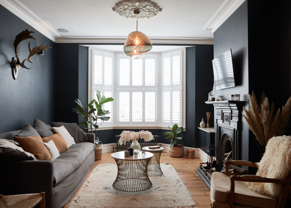 Стильный дизайн: гостиная комната в стиле неоклассика (современная классика) с черными стенами, паркетным полом среднего тона, стандартным камином, телевизором на стене и коричневым полом - последний тренд