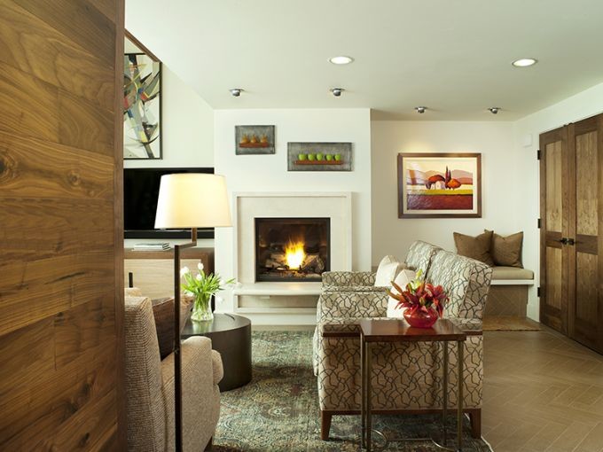 デンバーにある中くらいなトラディショナルスタイルのおしゃれなリビング (白い壁、セラミックタイルの床、標準型暖炉、漆喰の暖炉まわり、壁掛け型テレビ) の写真