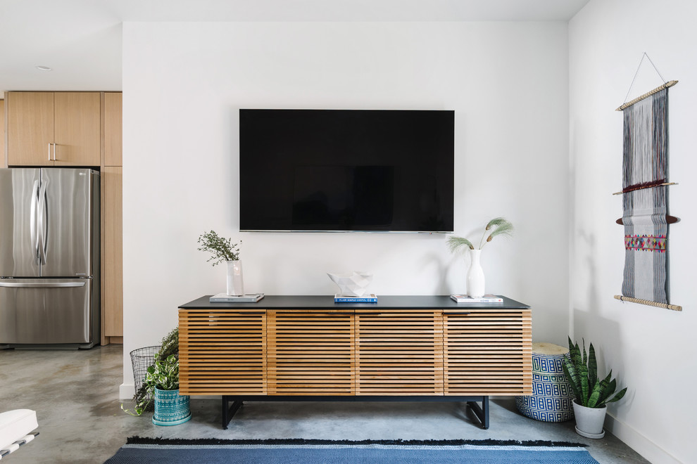 Идея дизайна: открытая, парадная гостиная комната среднего размера в стиле модернизм с белыми стенами, бетонным полом, серым полом и телевизором на стене без камина