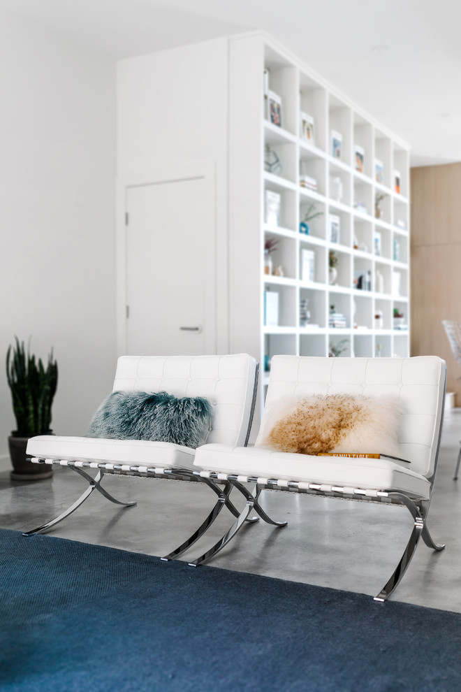 Immagine di un soggiorno moderno di medie dimensioni e aperto con pareti bianche, pavimento in cemento, pavimento grigio, sala formale, nessun camino e TV a parete