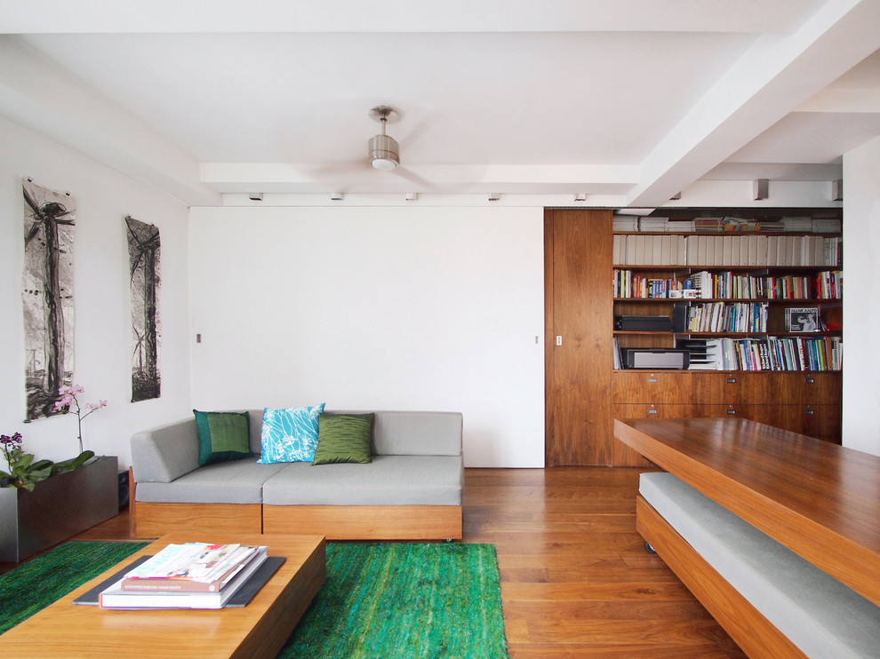 Immagine di un soggiorno moderno con libreria e pareti bianche