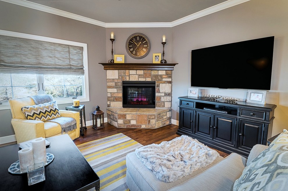 This is an example of a medium sized traditional open plan living room in Other with grey walls, dark hardwood flooring, a corner fireplace, a stone fireplace surround, a wall mounted tv and brown floors.