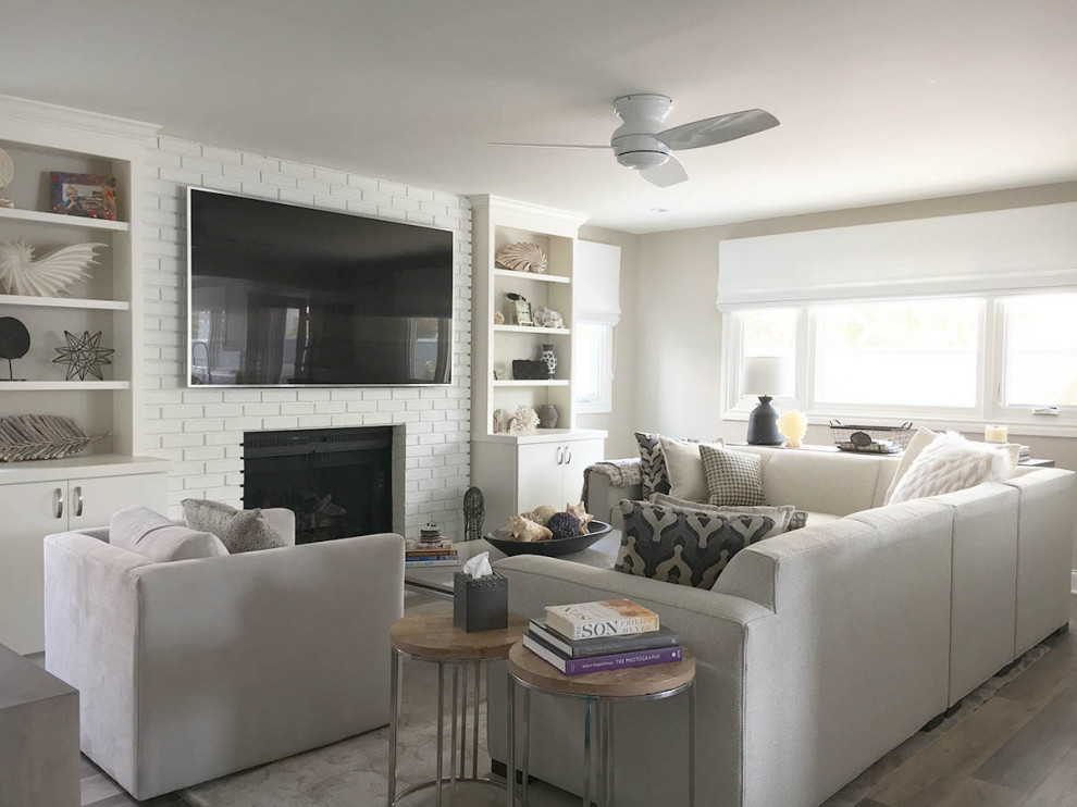 デンバーにある高級な広いトランジショナルスタイルのおしゃれなLDK (グレーの壁、ラミネートの床、標準型暖炉、レンガの暖炉まわり、壁掛け型テレビ、グレーの床) の写真