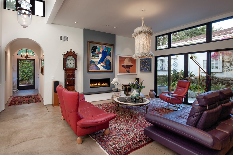 サンタバーバラにある高級な中くらいな地中海スタイルのおしゃれなLDK (白い壁、コンクリートの床、横長型暖炉、漆喰の暖炉まわり、テレビなし、赤いソファ) の写真