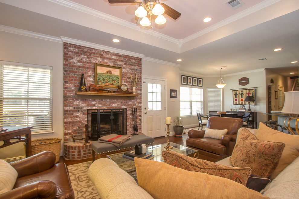 This is an example of a medium sized classic formal open plan living room in Other with grey walls, concrete flooring, a standard fireplace, a brick fireplace surround, a concealed tv and brown floors.