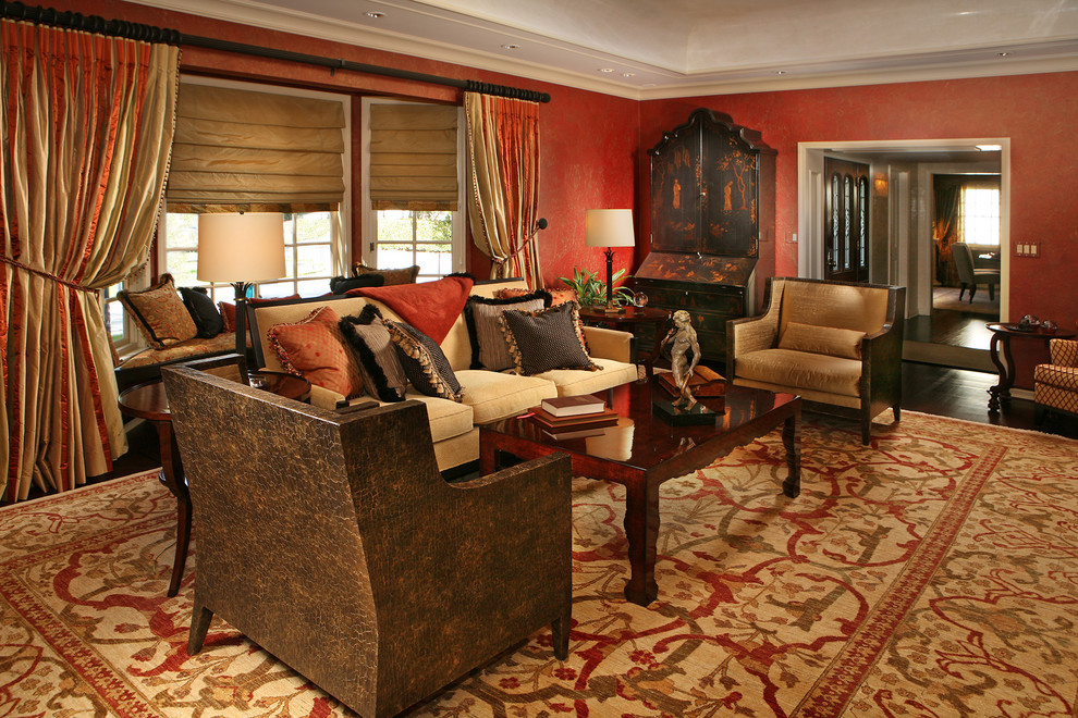 This is an example of a large classic formal enclosed living room in Los Angeles with red walls, dark hardwood flooring, no fireplace and no tv.