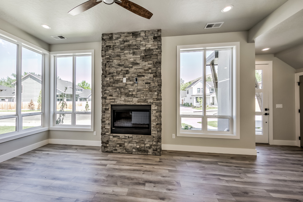 Mittelgroßes, Fernseherloses Klassisches Wohnzimmer mit beiger Wandfarbe, dunklem Holzboden, Kamin, Kaminumrandung aus Stein und braunem Boden in Boise