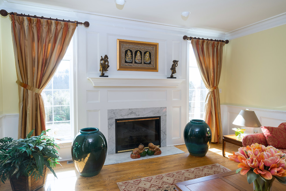 Cette image montre un grand salon traditionnel fermé avec une salle de réception, un mur jaune, un sol en bois brun, une cheminée standard, un manteau de cheminée en bois et un sol marron.