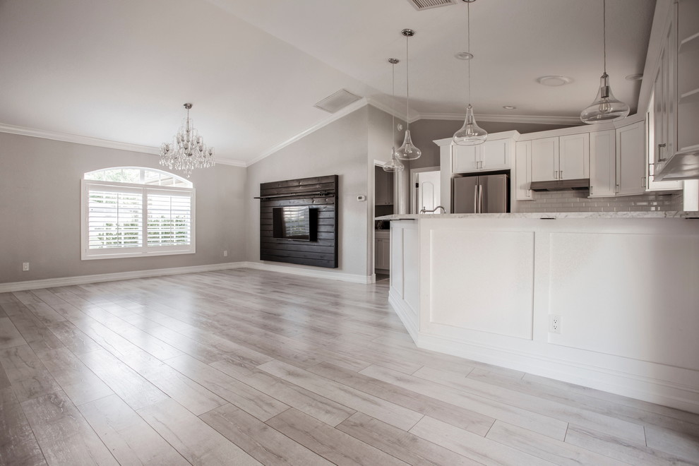 Großes, Offenes Klassisches Wohnzimmer ohne Kamin mit grauer Wandfarbe, hellem Holzboden, TV-Wand und grauem Boden in Tampa