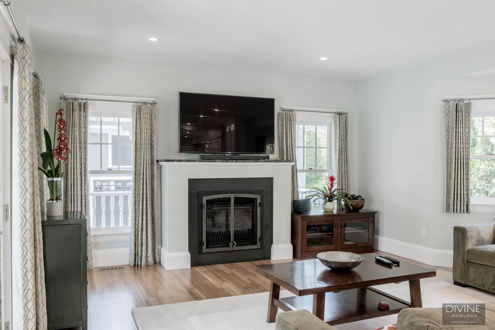 Cette image montre un grand salon traditionnel ouvert avec un mur gris, parquet clair, une cheminée standard, un manteau de cheminée en plâtre, un téléviseur fixé au mur et un sol beige.