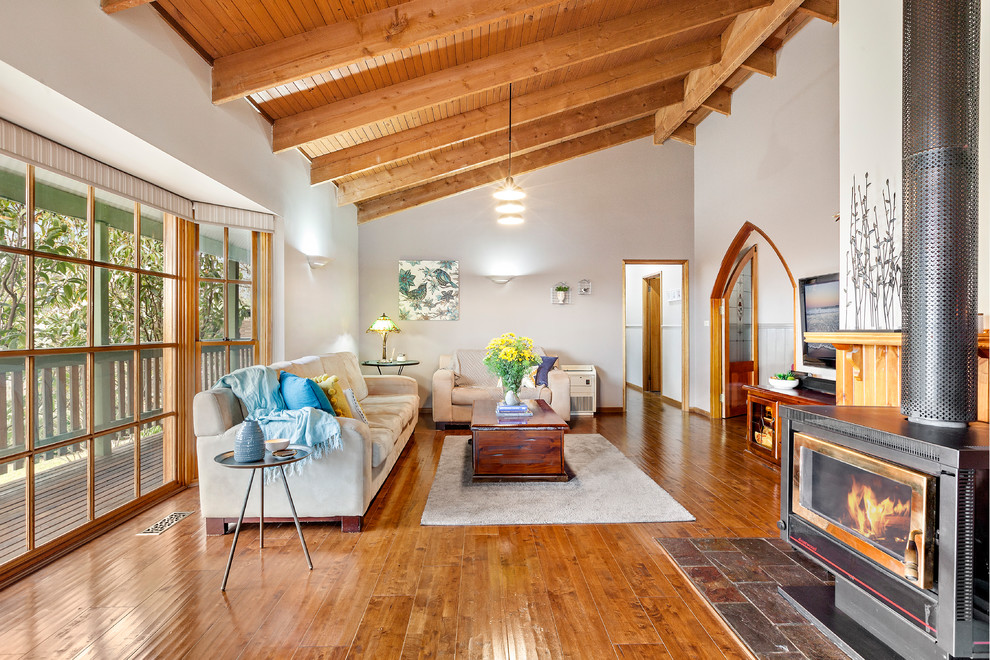 Offenes Klassisches Wohnzimmer mit weißer Wandfarbe, braunem Holzboden, Kaminofen und braunem Boden in Melbourne