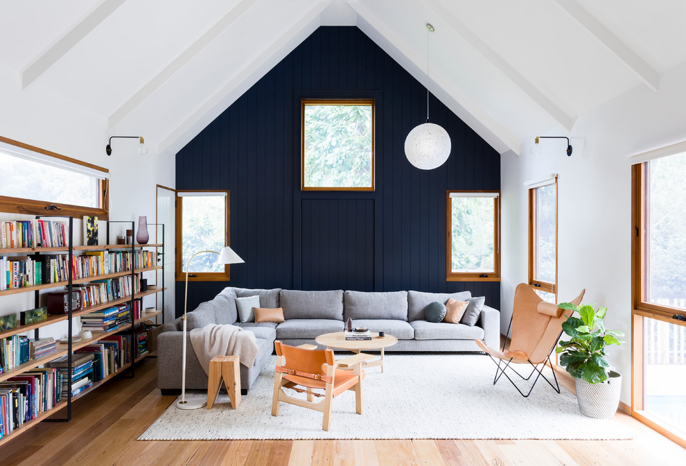 Idee per un soggiorno classico aperto con libreria, parquet chiaro e pareti blu