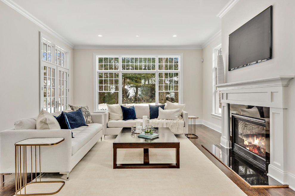Klassisches Wohnzimmer mit beiger Wandfarbe, braunem Holzboden, Kamin, TV-Wand und braunem Boden in New York