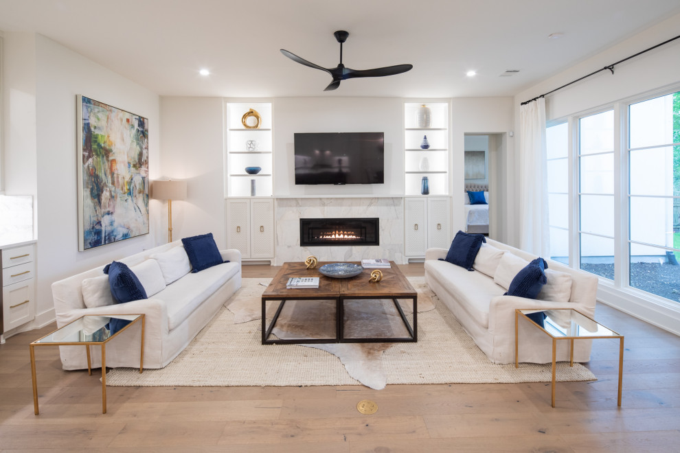 Mid-sized transitional open concept light wood floor and brown floor living room photo in Austin with white walls, a standard fireplace, a tile fireplace and a wall-mounted tv