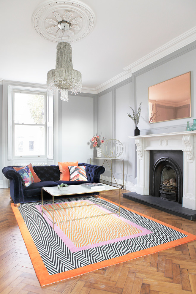 Immagine di un soggiorno classico con pareti grigie, pavimento in legno massello medio, camino classico e nessuna TV