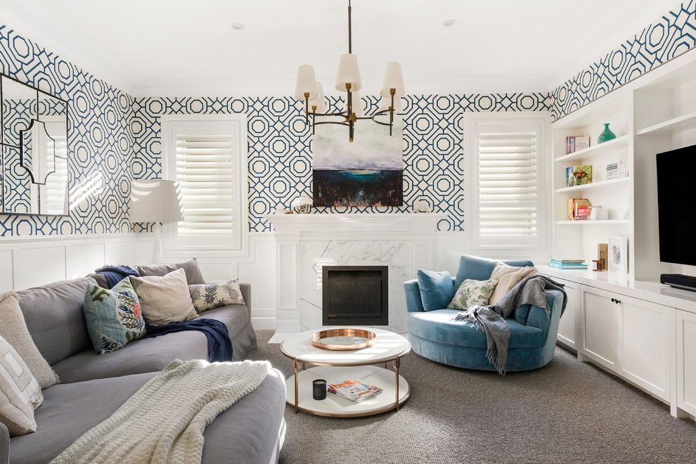 На фото: гостиная комната:: освещение в стиле неоклассика (современная классика) с синими стенами, ковровым покрытием, стандартным камином, фасадом камина из камня, мультимедийным центром и серым полом
