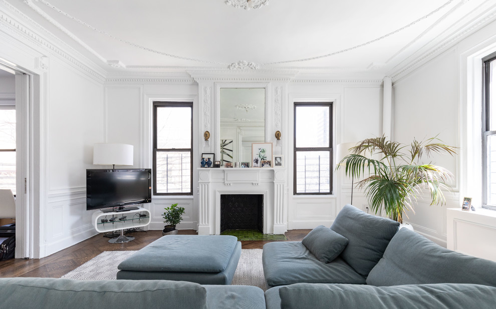 Ispirazione per un soggiorno chic con pareti bianche, pavimento in legno massello medio, camino classico, TV autoportante e pavimento marrone