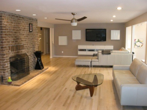 Example of a mid-sized minimalist open concept light wood floor and beige floor living room design in Baltimore with brown walls, a standard fireplace, a brick fireplace and a wall-mounted tv