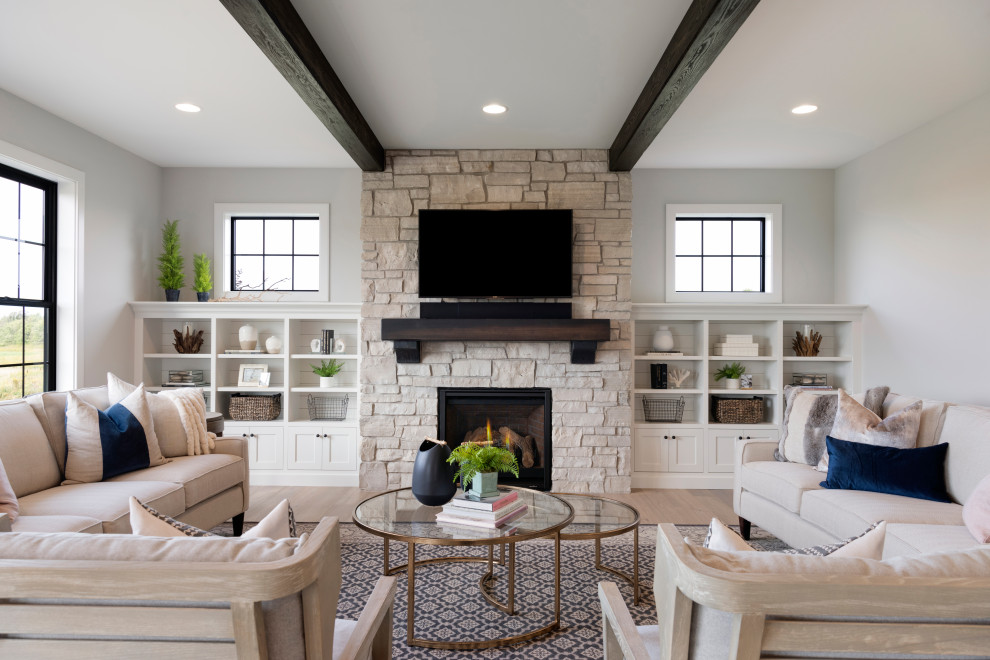 Пример оригинального дизайна: гостиная комната в стиле неоклассика (современная классика) с серыми стенами, светлым паркетным полом, печью-буржуйкой, фасадом камина из камня, телевизором на стене и ковром на полу