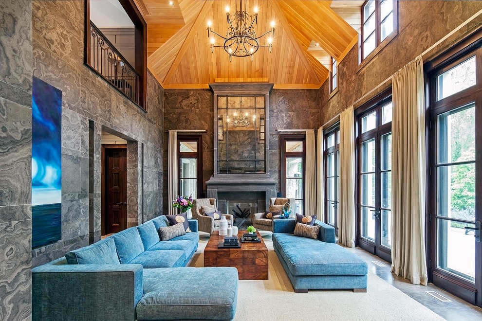 На фото: огромная гостиная комната в стиле неоклассика (современная классика) с стандартным камином и синим диваном с