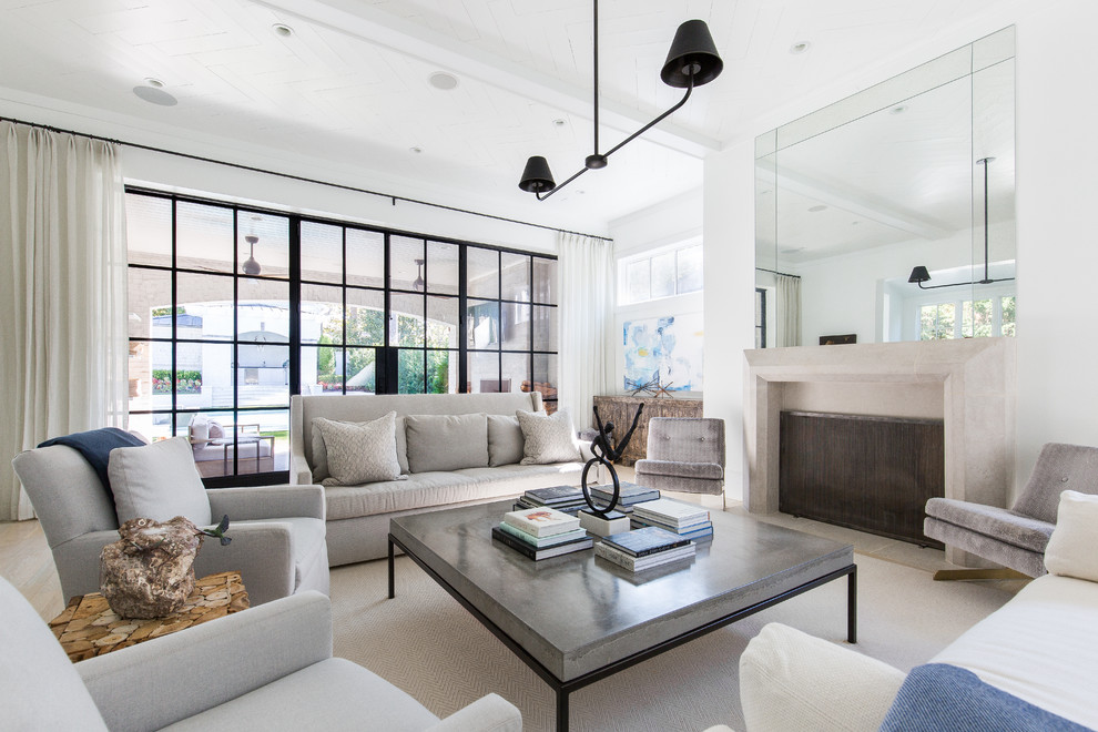 Exemple d'un grand salon bord de mer avec un mur blanc, parquet clair, une cheminée standard et un manteau de cheminée en pierre.