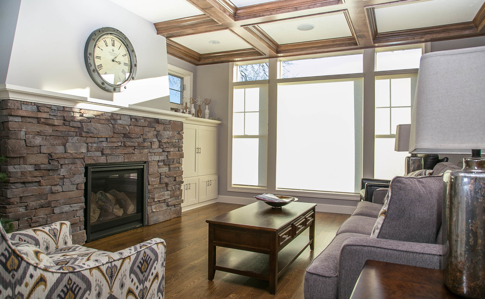 Transitional open concept medium tone wood floor living room photo in Minneapolis with gray walls, a standard fireplace, a stone fireplace and a concealed tv
