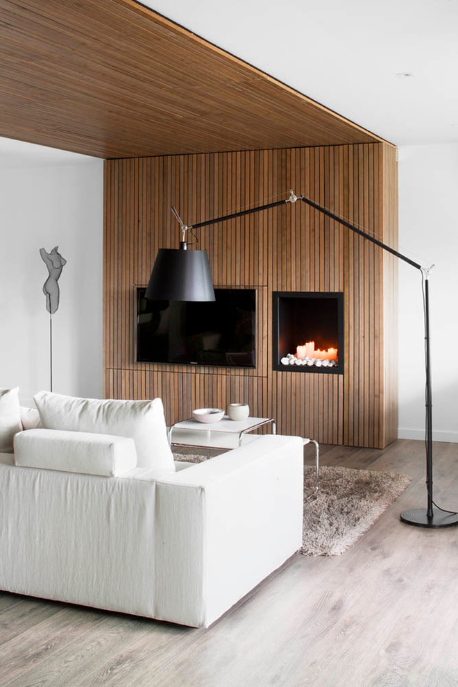 Mittelgroßes, Repräsentatives, Offenes Modernes Wohnzimmer mit TV-Wand, weißer Wandfarbe, hellem Holzboden, Kamin und grauem Boden in Barcelona