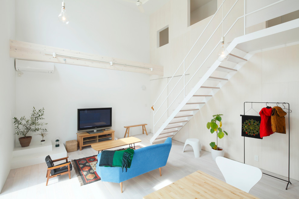 Imagen de salón abierto contemporáneo con paredes blancas, televisor independiente y suelo beige