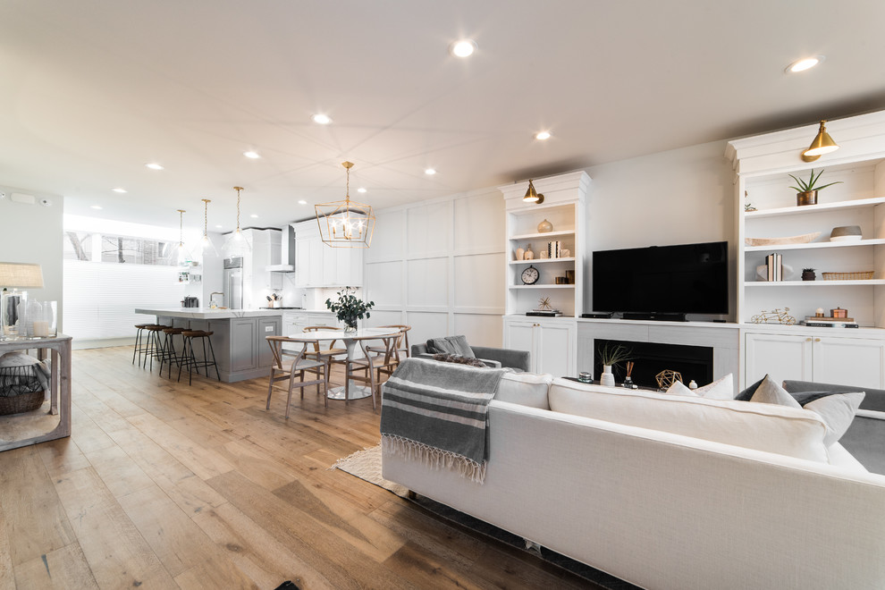 Inspiration for a mid-sized transitional open concept medium tone wood floor and brown floor living room remodel in Chicago with white walls, a standard fireplace and a media wall